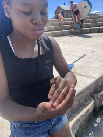 A student shows off a crawdad on her hand during the AXL day of fishing education.