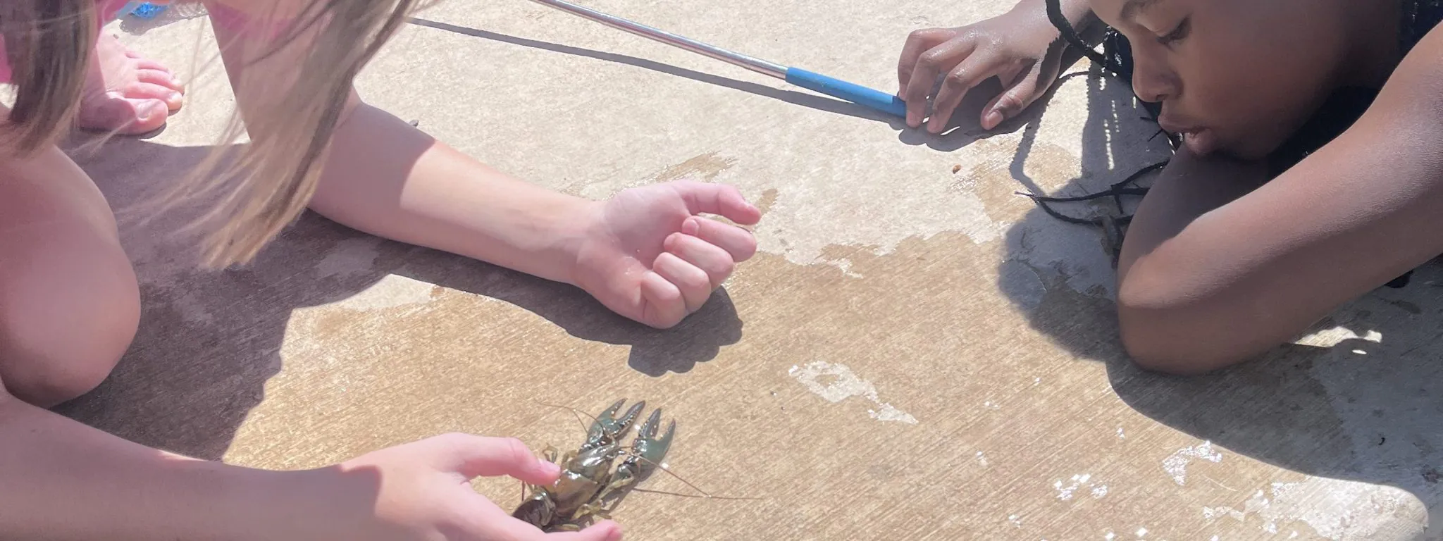 AXL student check out a crawdad they caught in the water during their day of fishing education.