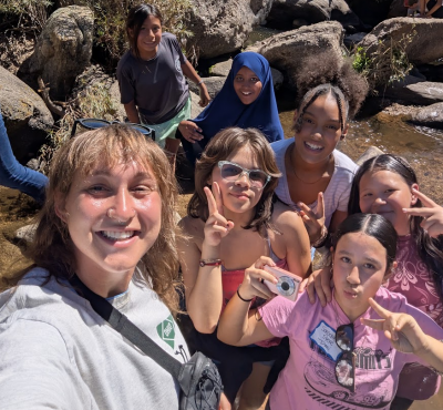 Hannah poses in a creek with her students.