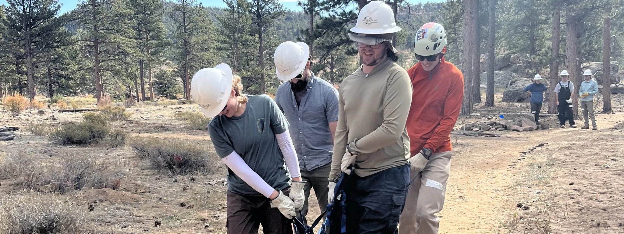 Cottonwood alumni work together to move rock in groups of 4 during a trail restoration project.