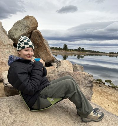 One Cottonwood alum enjoys a warm drink while sitting on a rock by the lake.